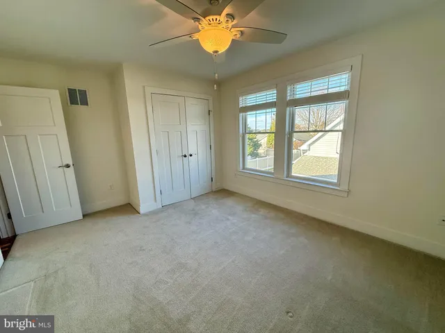 an empty room with windows and fan