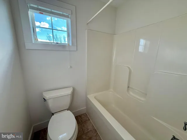 a white toilet sitting next to a bath tub