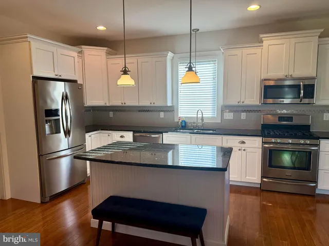 a kitchen with kitchen island granite countertop a sink a counter space stainless steel appliances and cabinets