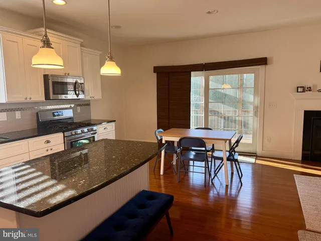 a kitchen with stainless steel appliances granite countertop a stove top oven a dining table and chairs with wooden floor