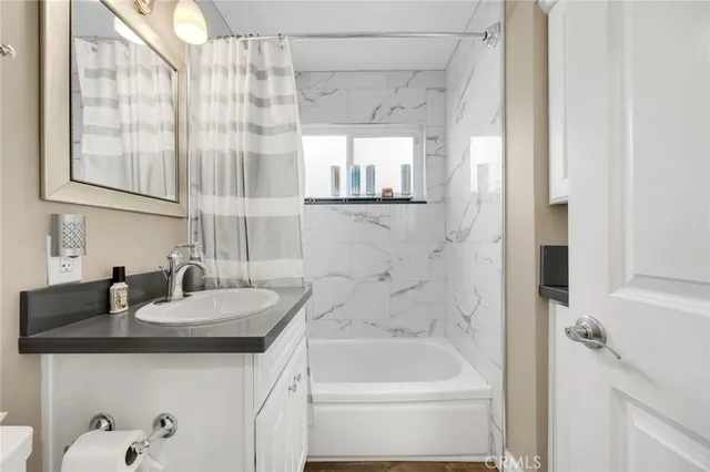 a bathroom with a granite countertop sink a mirror and a bathtub