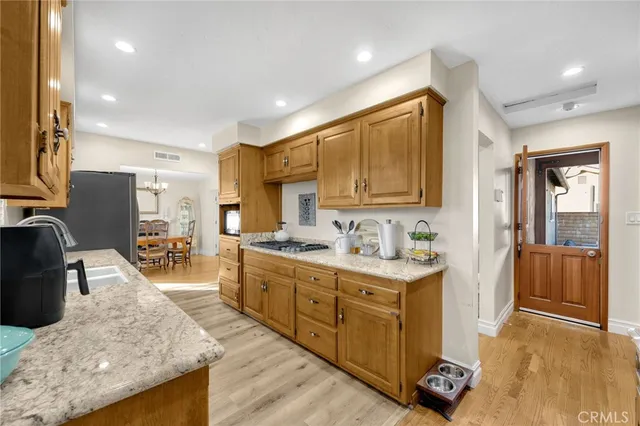 a kitchen with stainless steel appliances granite countertop a stove top oven a sink dishwasher a refrigerator and cabinets with wooden floor