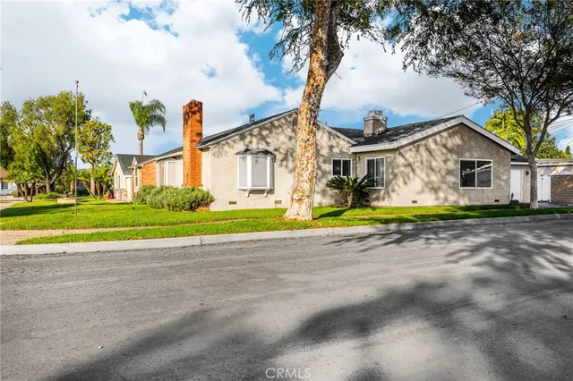 a view of a house with a big yard and palm trees