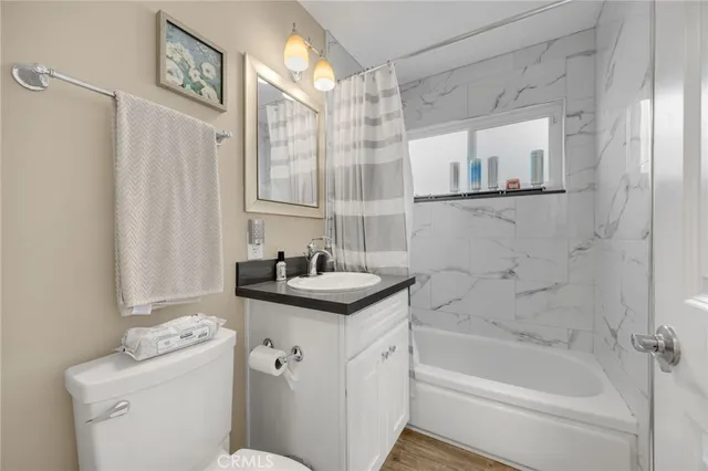 a bathroom with a granite countertop sink a toilet and shower