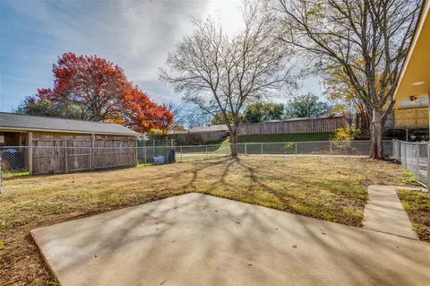 a backyard of a house with large trees and outdoor seating