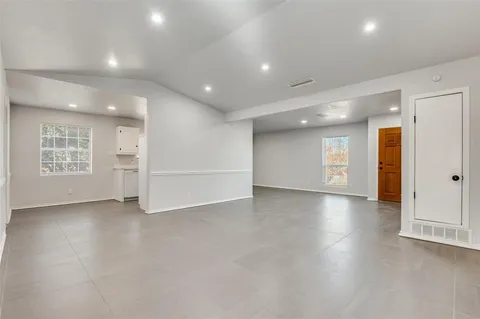 an empty room with windows and entrance to other room