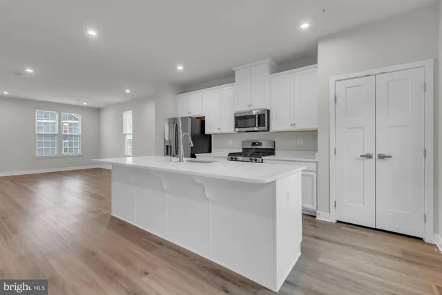 a kitchen with kitchen island white cabinets and wooden floor