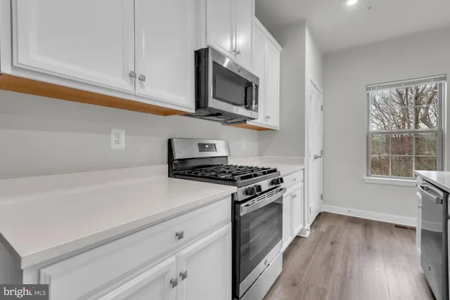 a kitchen with stainless steel appliances a white cabinet and a stove top oven
