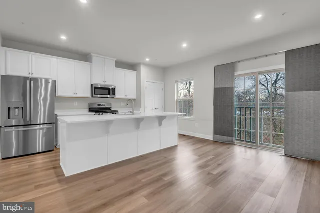 a kitchen with wooden floors white cabinets and stainless steel appliances