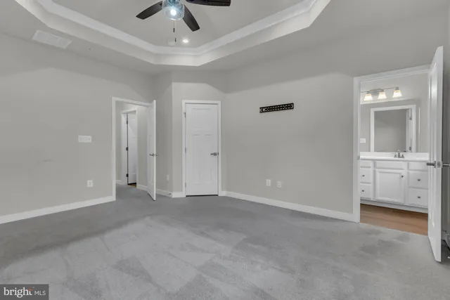 an empty room with chandelier fan and windows