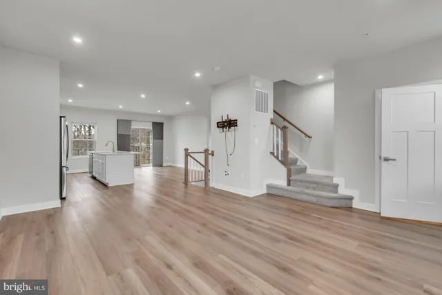 a view of an empty room with wooden floor and stairs