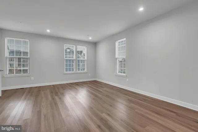 a view of an empty room with wooden floor and windows
