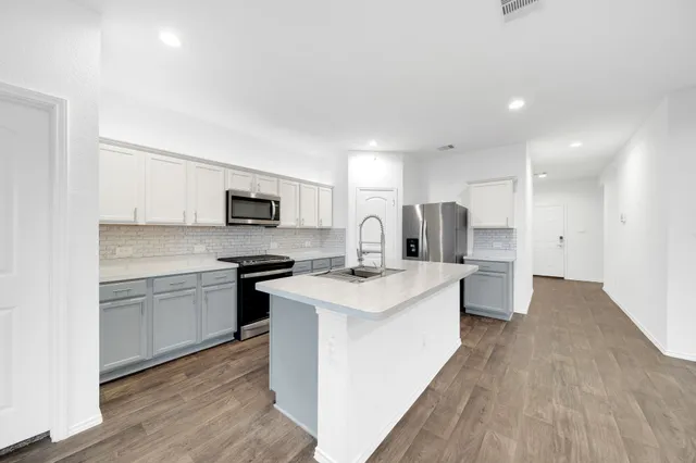a kitchen with a sink a stove a refrigerator and white cabinets