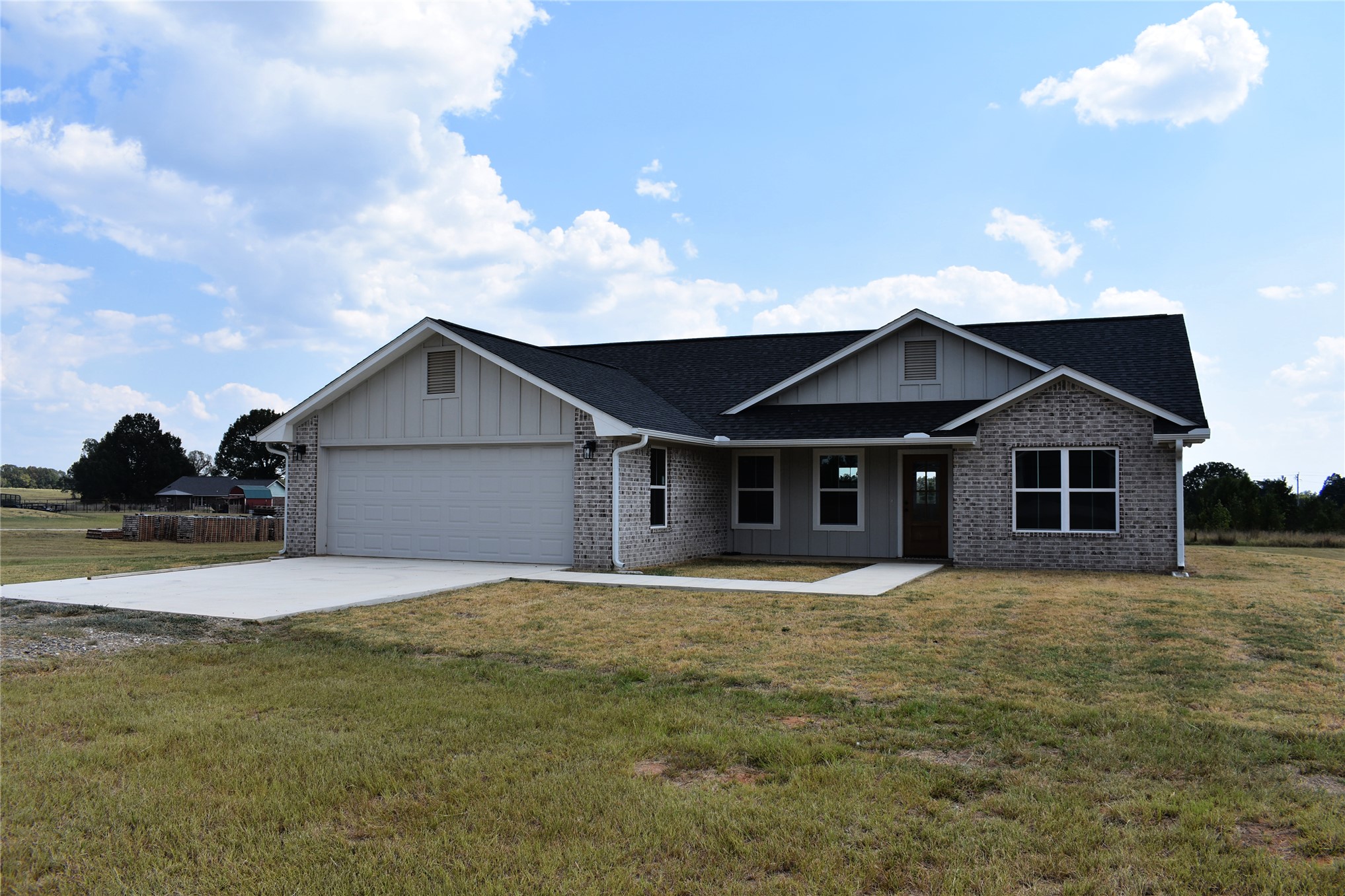 2915 East 2090 Road Hugo, OK 74743 - Photo 1 of 27 Brick and siding exterior with a dark shingle roof, attached garage, and concrete driveway