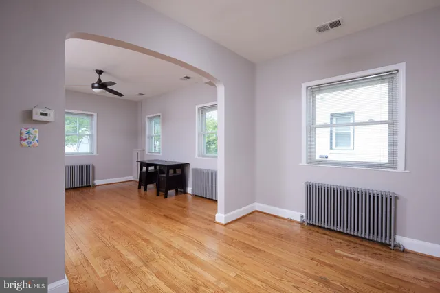 an empty room with windows a fireplace and wooden floor