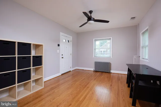 a view of an empty room with a window and wooden floor