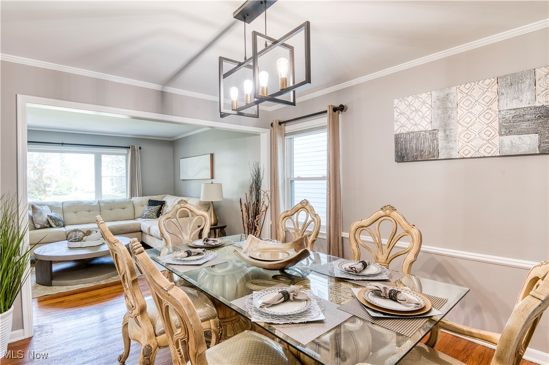 4520 Birchwold Road Cleveland, OH 44121 - Photo 12 of 40 Dining room featuring light wood-type flooring, elegant glass table, chandelier and ornamental molding