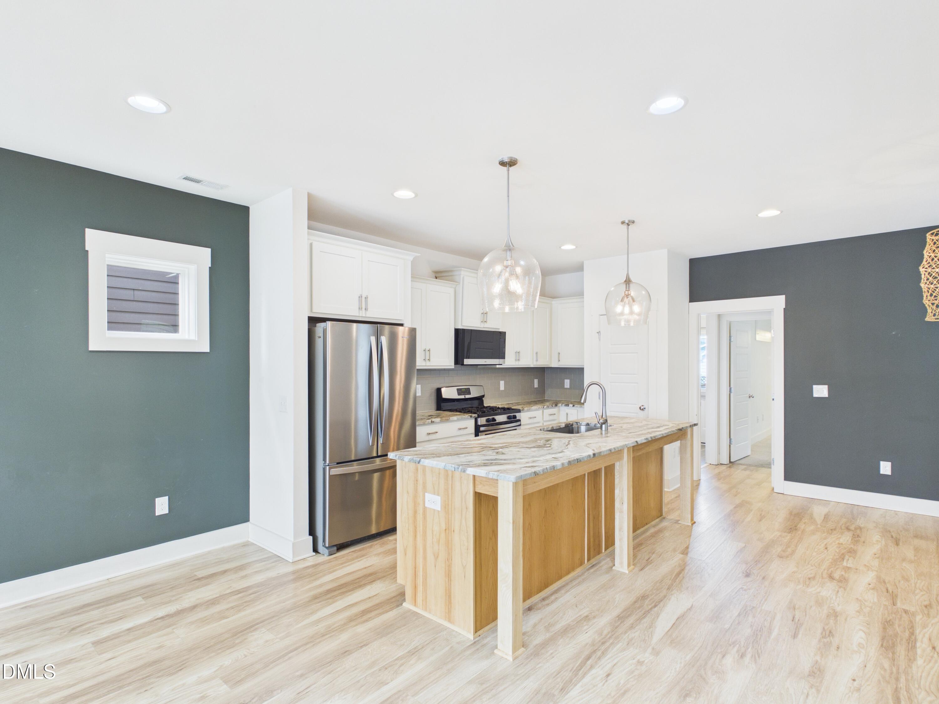 748 Groveview Wendell, NC 27591 - Photo 9 of 38 a kitchen with stainless steel appliances granite countertop a refrigerator a stove and a wooden floors