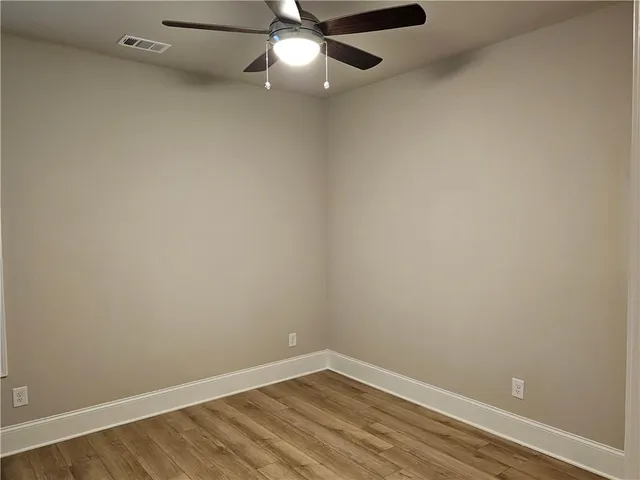 an empty room with a ceiling fan and wooden floor