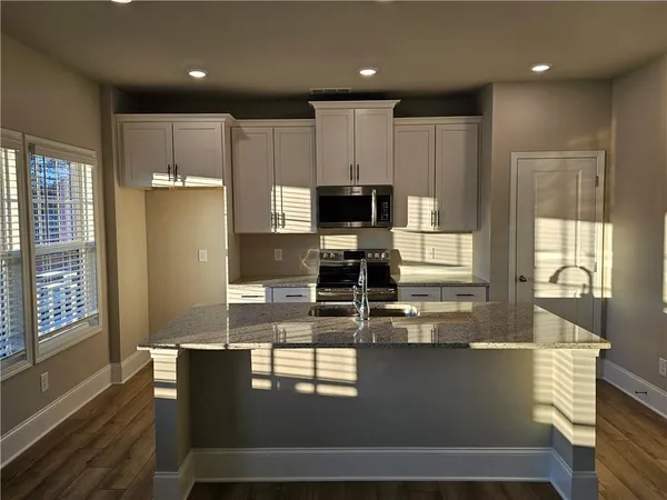 a kitchen with kitchen island a large counter top space a sink stainless steel appliances and cabinets