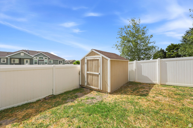 5485 Heather Way Tooele, UT 84074 - Photo 34 of 41 Backyard space featuring a storage shed with a shingle roof, a white privacy fence, and a grass lawn