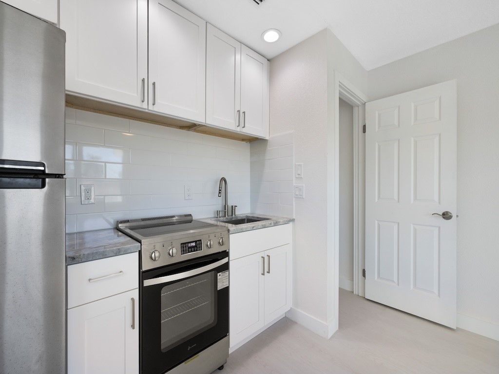 741 Hernando Street Fort Pierce, FL 34949 - Photo 12 of 36 a kitchen with granite countertop white cabinets and a stove top oven