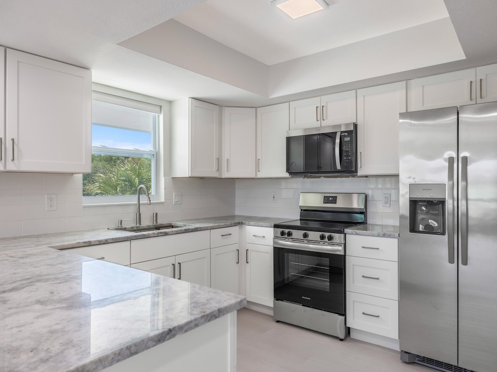741 Hernando Street Fort Pierce, FL 34949 - Photo 31 of 36 a kitchen with white cabinets stainless steel appliances and a window