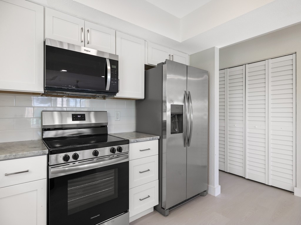 741 Hernando Street Fort Pierce, FL 34949 - Photo 32 of 36 a kitchen with stainless steel appliances white cabinets and a stove top oven