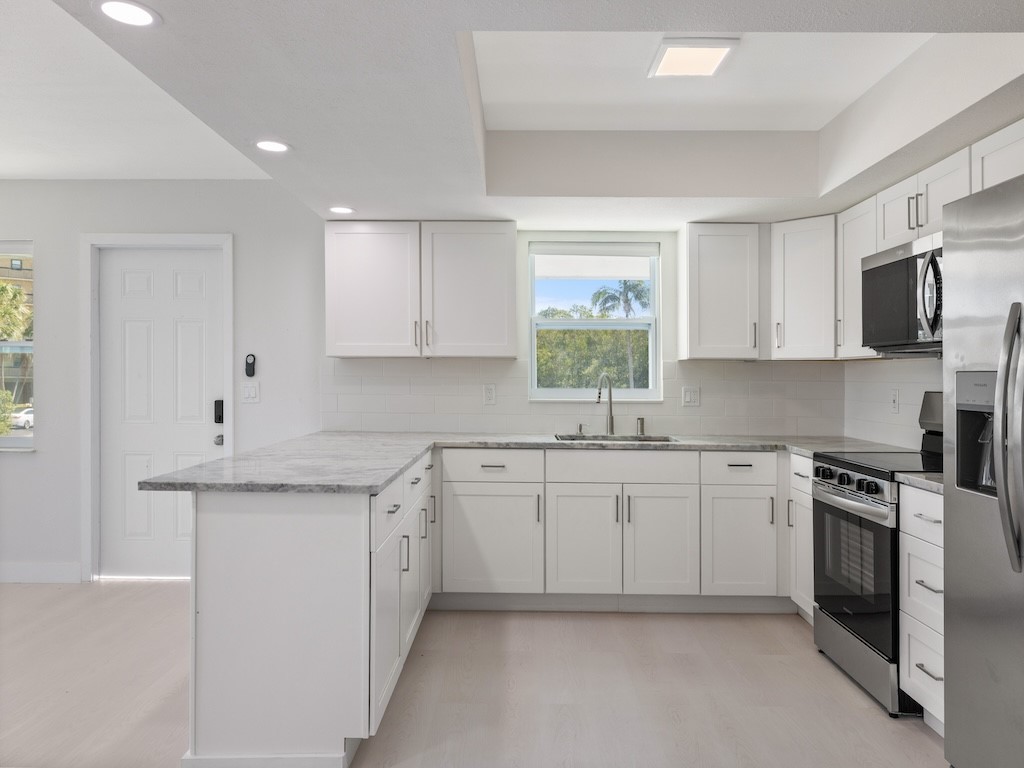 741 Hernando Street Fort Pierce, FL 34949 - Photo 33 of 36 a kitchen with granite countertop white cabinets white stainless steel appliances with a sink and dishwasher