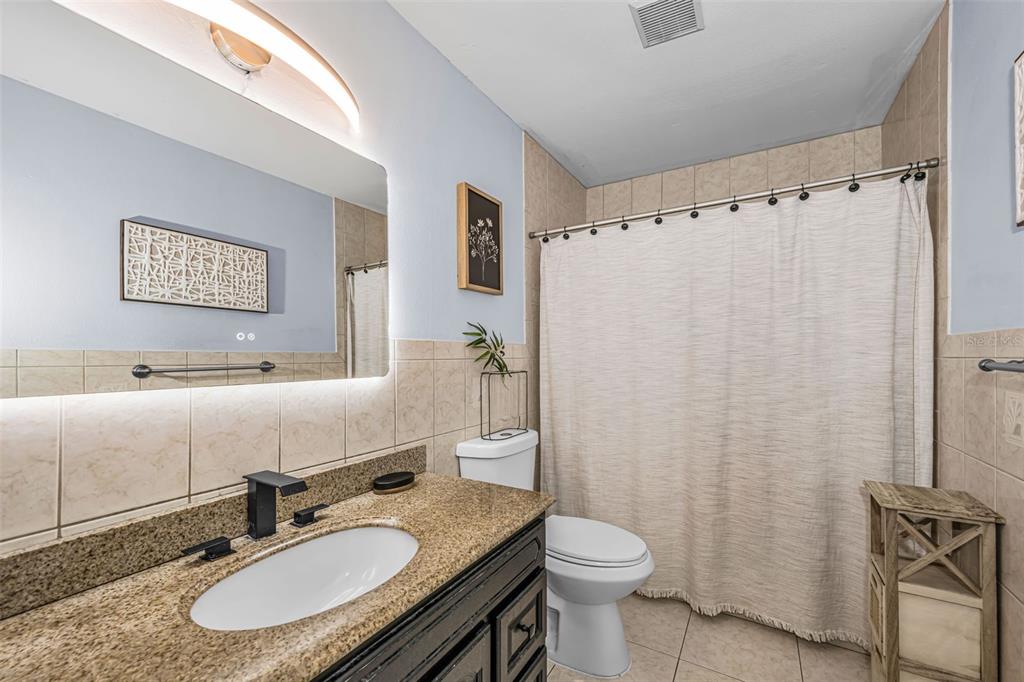 6009 Bayway Court New Port Richey, FL 34652 - Photo 57 of 93 a bathroom with a granite countertop sink toilet a mirror a shower curtain