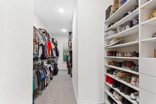 a view of walk in closet with clothes and shoes
