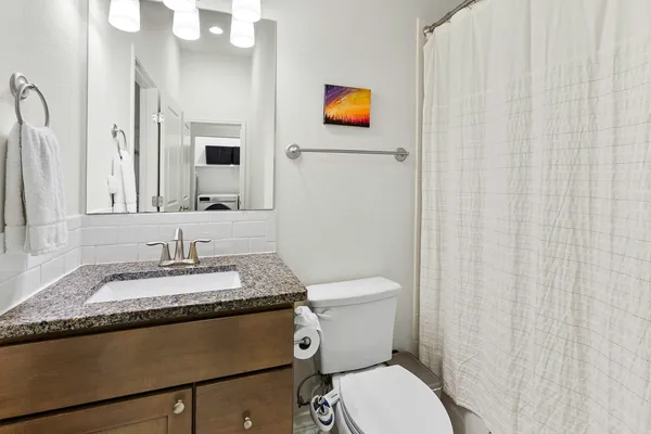 a bathroom with a granite countertop sink and a mirror with toilet