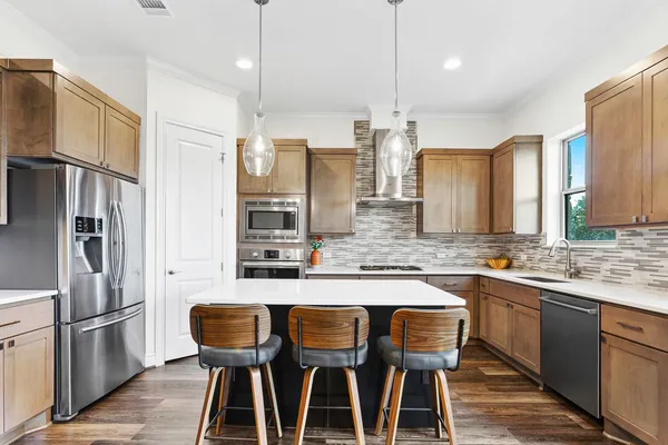 a kitchen with granite countertop stainless steel appliances a sink stove and refrigerator