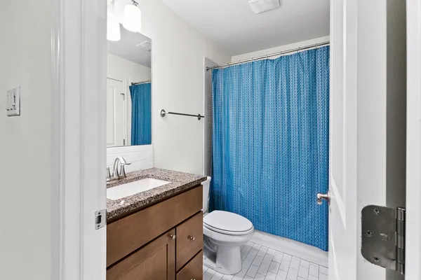 a bathroom with a granite countertop sink toilet and mirror