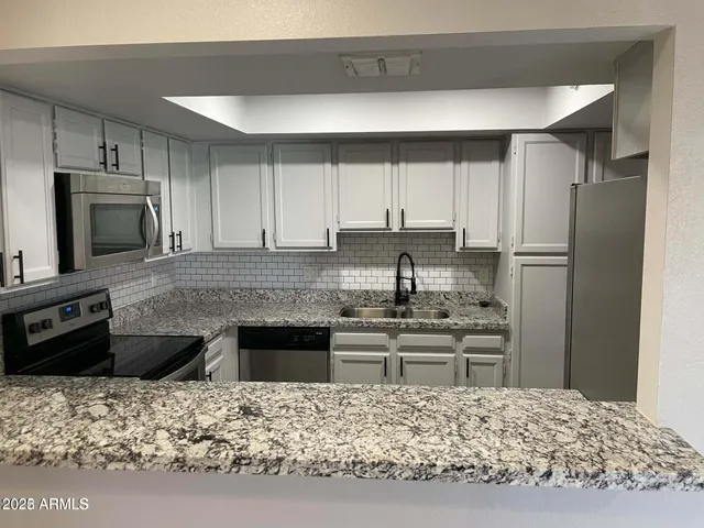 a kitchen with kitchen island granite countertop a refrigerator stove top oven and sink