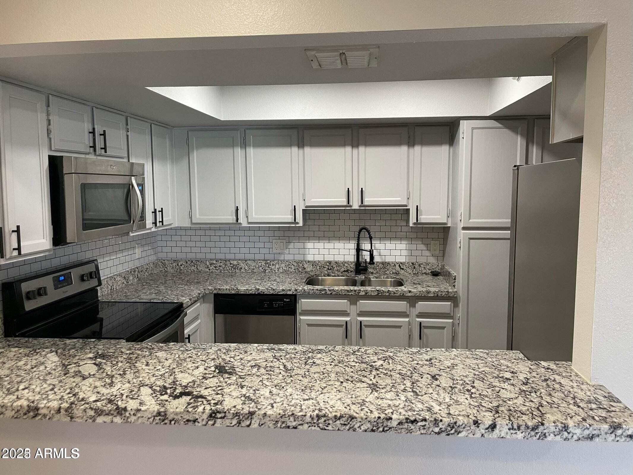 1645 West Baseline Road, Unit 2171 Mesa, AZ 85202 - Photo 1 of 11 a kitchen with kitchen island granite countertop a refrigerator stove top oven and sink