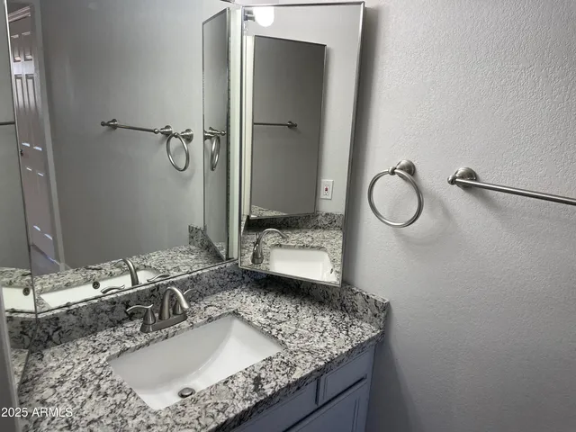 a bathroom with a granite countertop sink and a mirror