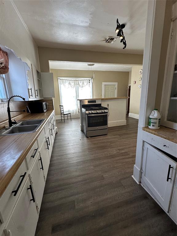 Kitchen with white cabinetry, stainless steel appliances, and dark wood-style floors