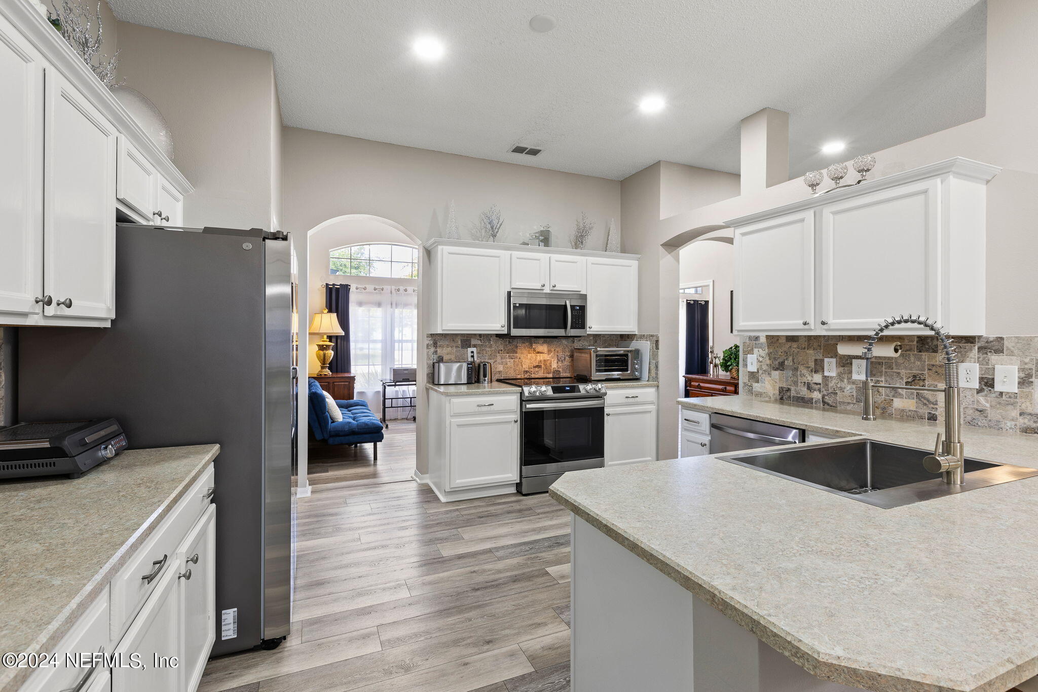 18 Underwick Path Palm Coast, FL 32164 - Photo 9 of 36 a kitchen with stainless steel appliances granite countertop a refrigerator a stove top oven a sink dishwasher and white cabinets with wooden floor
