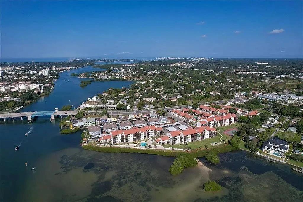 an aerial view of a city with lots of residential buildings ocean and mountain view in back