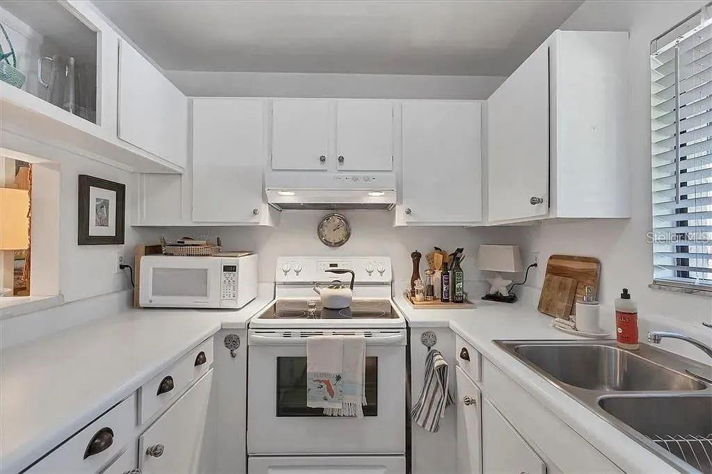 1650 Stickney Point Road, Unit 50202 Sarasota, FL 34231 - Photo 7 of 46 a kitchen with white cabinets and white appliances