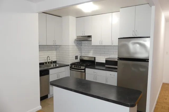 a kitchen with stainless steel appliances granite countertop a refrigerator a sink a stove and white cabinets