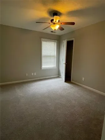 an empty room with a chandelier fan and windows