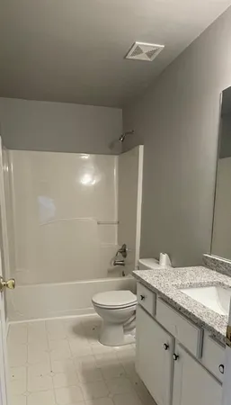 a bathroom with a granite countertop sink a toilet and mirror
