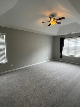 an empty room with a chandelier fan and windows
