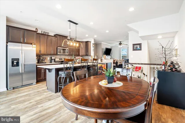 a kitchen with stainless steel appliances kitchen island granite countertop a refrigerator a stove a sink a dining table and chairs