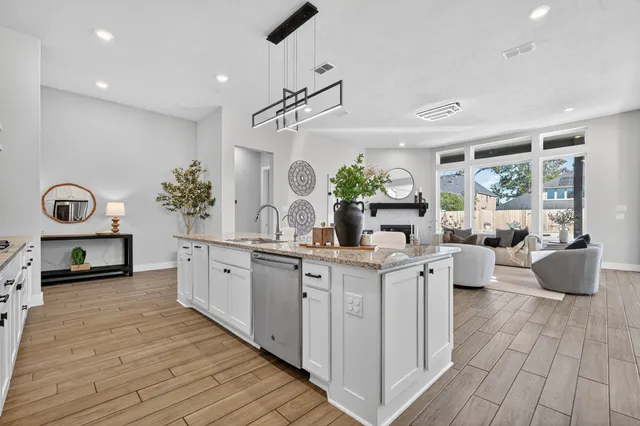 a large white kitchen with stainless steel appliances a lot of counter space and a wooden floors
