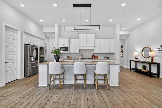 a kitchen with stainless steel appliances granite countertop a dining table chairs stove a refrigerator and cabinets