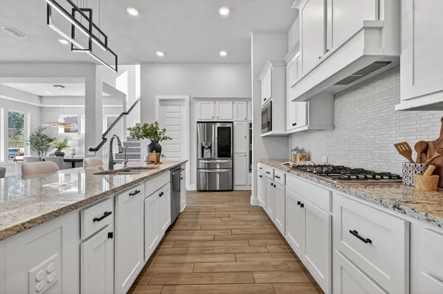 a large kitchen with stainless steel appliances granite countertop a lot of counter space and wooden floors