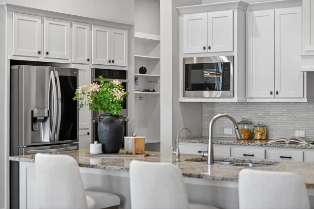 a kitchen with stainless steel appliances granite countertop a refrigerator a sink a stove and white cabinets